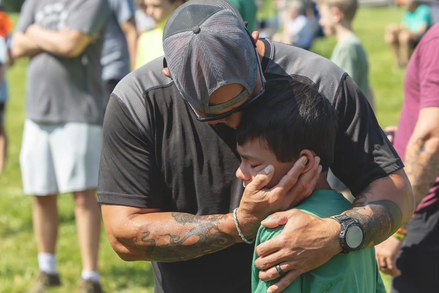 A father embracing his son at an outdoor gathering